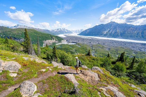 Young man on a hiking trail, view of impressive mountain landscape with Matanuska glacier and