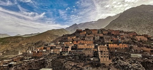 Dramatic shot of a mountain village with clay-colored houses nestled against a range of hills in