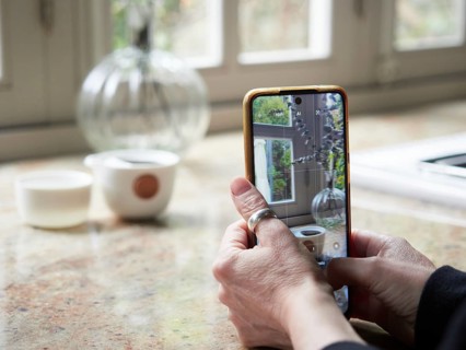 Close up view, female hands holding smartphone taking a photo of a cup on kitchen countertop. Out
