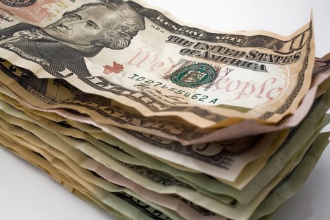 Close-up of stack of creased and wrinkled US paper currency bank notes on white background, Studio
