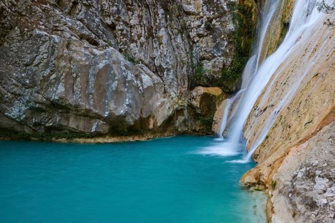 Close-up of a waterfall flowing into a turquoise pool surrounded by rocks, waterfalls, ponds,