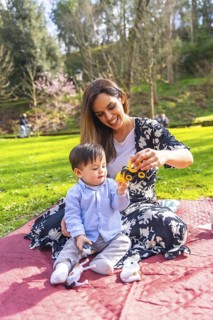 Mother and baby boy enjoying quality time together, playing with a toy truck on a blanket in a
