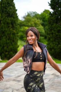 Vertical photo of a happy hispanic woman dancing salsa alone outdoors