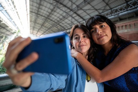A close-up image of a multiethnic lesbian couple capturing a selfie together. Their joyous