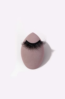 False eyelashes gracefully rests on a makeup sponge. The white background highlights the contrast,