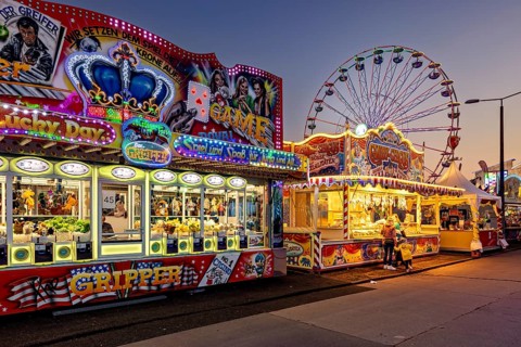 Colourful and lively fairground scene with illuminated carousel and Ferris wheel at night, carousel