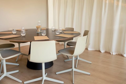 Modern boardroom with a round table and minimalist design. Neutral-toned chairs surround the table,