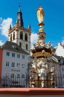 Baroque fountain with detailed sculptures in front of a historic tower in the old town,