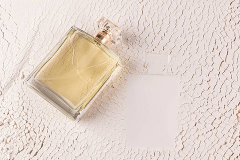 A stylish male perfume bottle lies on a textured, sand white surface, capturing an essence of