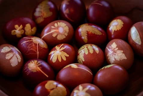 Easter eggs traditionally colored with onion skins, tights and small plants and flowers in a wooden