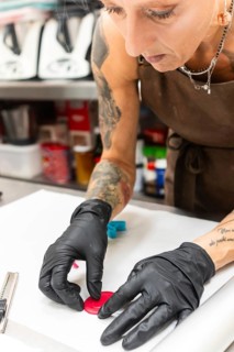 Skilled artisan in an Italian bakery, wearing black gloves and an apron, crafting intricate edible