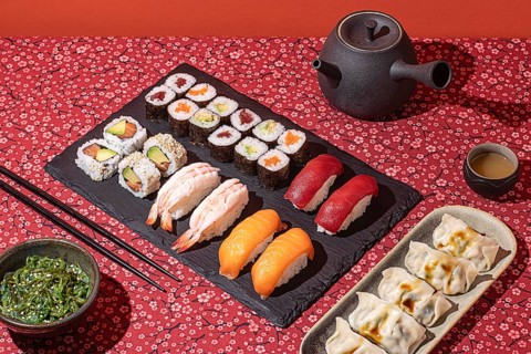 Top-down view of an elegant sushi dinner, presented on a floral red tablecloth with dramatic