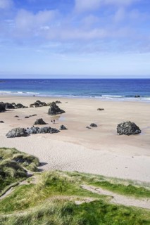 Tourists walking on sandy beach with rocks near Durness, Sutherland, Scottish Highlands, Scotland,