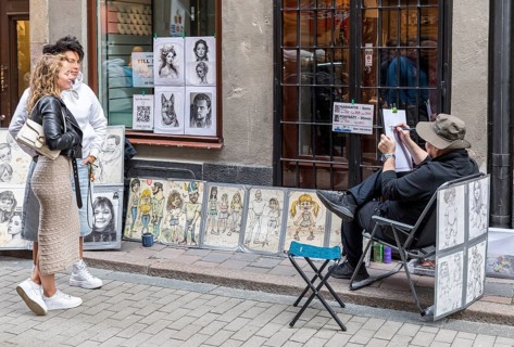 Young couple having a portrait taken by a street draftsman, Västerlånggatan in the old town of