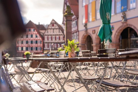 Sun-drenched table with Easter decoration in front of half-timbered houses on a market square,