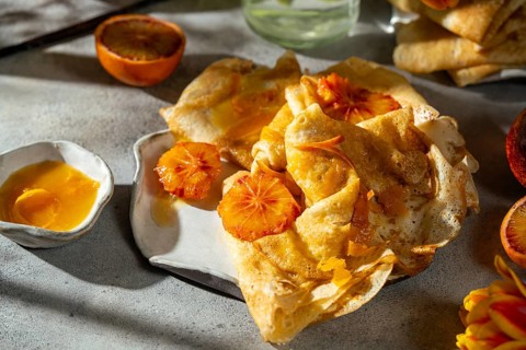 A delicious serving of Crepes Suzette, showcasing pancakes drenched in a rich caramelized sugar,