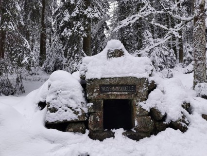 Fountain and spring of the White Main, snow-covered stone monument in the forest, surrounded by