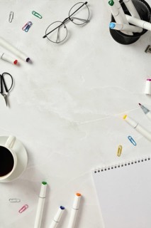 Top view of a creative and organized workspace featuring sketchbook, colorful markers, scissors,
