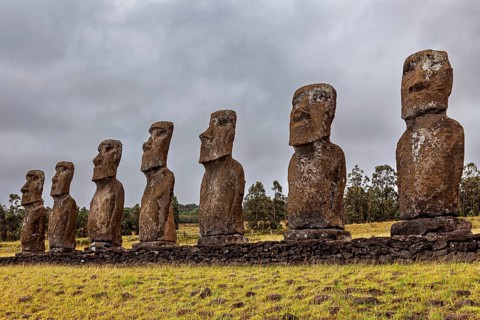 Several Moai statues stand in line under a cloudy sky on Easter Island, The Moai statues on Easter