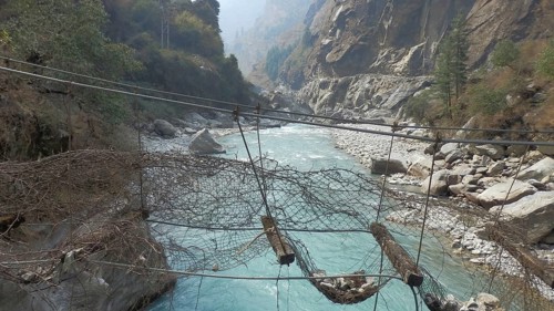 View of a river in a gorge with an old suspension bridge, trekking at Annapurna Circuit, Manang,