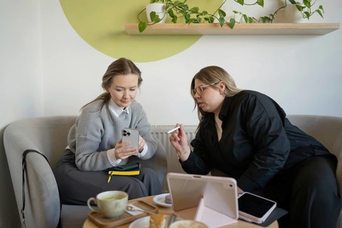 Two women engaging in conversation over coffee in a modern cafe setting. They are discussing work,