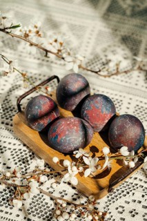 Artistic Easter eggs with a unique galaxy pattern displayed on a wooden tray, adorned with blooming