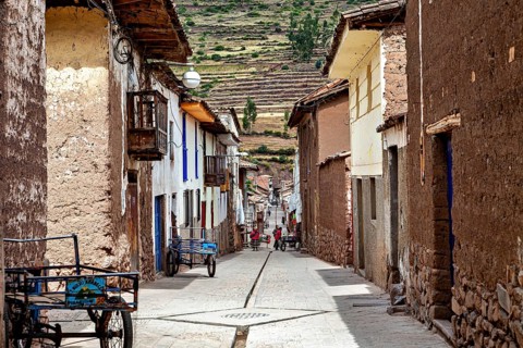 A narrow street with traditional houses and Andes in the background, the city of Ollantaytambo in