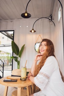 A young American Latin woman sits at a stylish cafe table, enjoying a refreshing drink. She exudes