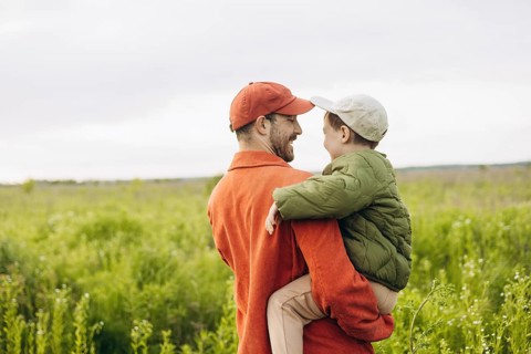 A heartwarming scene of a father and his young son walking together through an open field. The bond