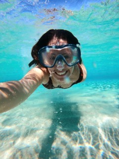 A woman enjoys snorkeling in the crystal-clear waters off the Greek coast. Her smile is visible
