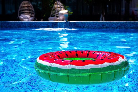 Colorful watermelon float in a bright blue swimming pool on a sunny day in summer