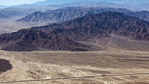 Wide desert landscape with distinctive mountains in the background, taken from the air on a clear