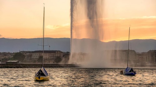 A breathtaking sunset view at Lake Geneva featuring the iconic Jet d'Eau fountain with colorful