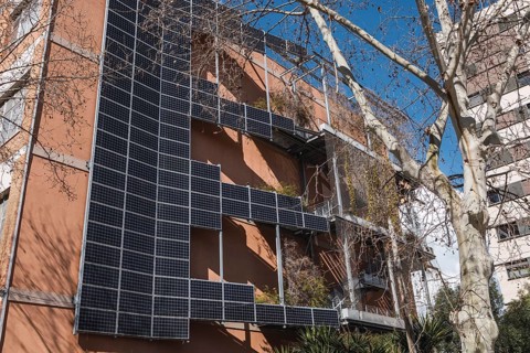 Solar panels cover the facade of a modern urban building, promoting sustainable energy. The