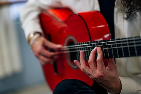 Anonymous Latin man playing red bass guitar in studio