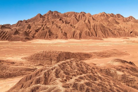 Vast red rock formations stretch across the arid landscape of Devil's Desert, Salta, Argentina,