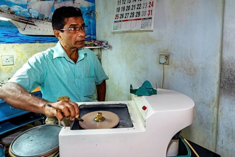 Man working with a machine in a room with a maritime poster on the wall, The gemstone cutters in