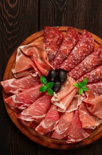 Assortment, sliced meat appetizer, prosciutto, salami and ham, with olives, breakfast, top view,