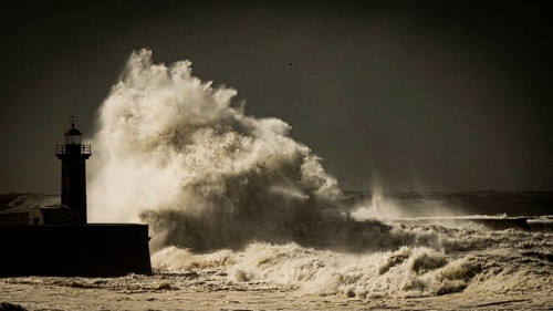 A lighthouse overlooks huge waves in stormy scenery, coast near Porto on the Caminho Portugues da