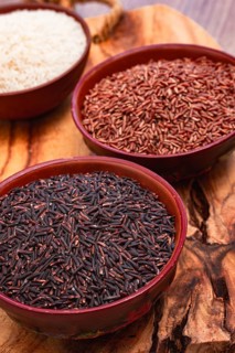 Set of red and black and white rice, in a bowl, on a wooden surface, rustic style, top view
