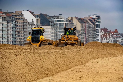Bulldozers when distributing sand on the beach in the town of Knokke-Heist, part of coastal