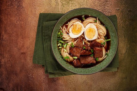 Asian noodles in broth, with beef and egg, top view, close-up, no people