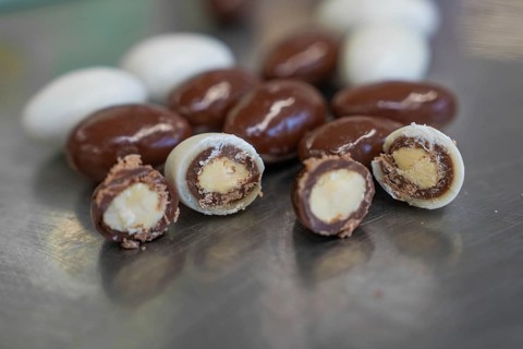 Various chocolate eggs on a metal surface, some cut in half to show the filling, Easter production