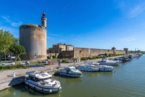 Yachts and motorboats are moored in the harbor on the Rhone-Sete Canal in front of the Tour de