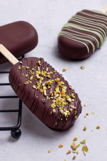 Gourmet chocolate covered ice creams garnished with matcha blend, presented elegantly on a white