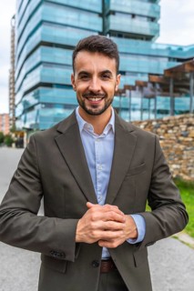 Vertical frontal portrait of a caucasian young businessman wearing suit standing smiling at camera