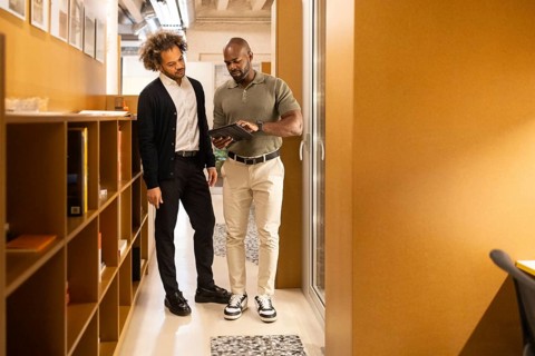 Two professionals engage in a discussion in a stylish coworking space in Barcelona, surrounded by