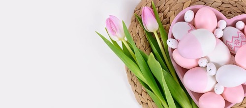Banner with Easter eggs in heart shaped plate and tulip flowers with copy space