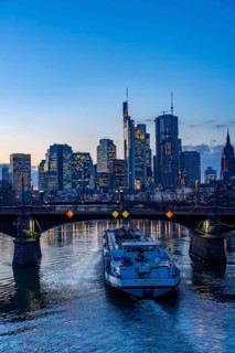 Skyline of the city centre of Frankfurt am Main, river Main, dusk, Ignatz-Bubis-Bridge, cargo ship,