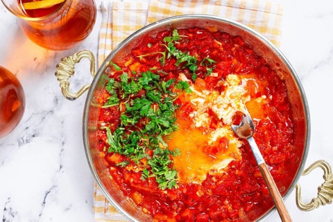 Traditional Turkish dish, scrambled eggs with tomatoes, Menemen, with herbs, in a frying pan,